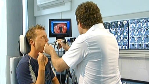 Arzt schaut Sänger mithilfe einer kleinen Optik in den Rachen