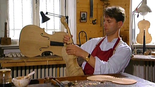 Geigenbauer Peter Greiner betrachtet eine seiner Geigen