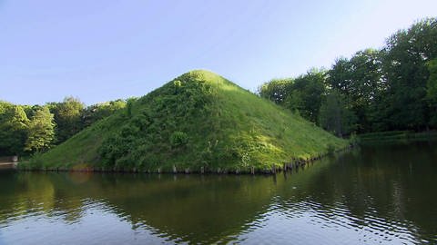 Eine Pyramide aus Gras ragt aus einem Fluss heraus.